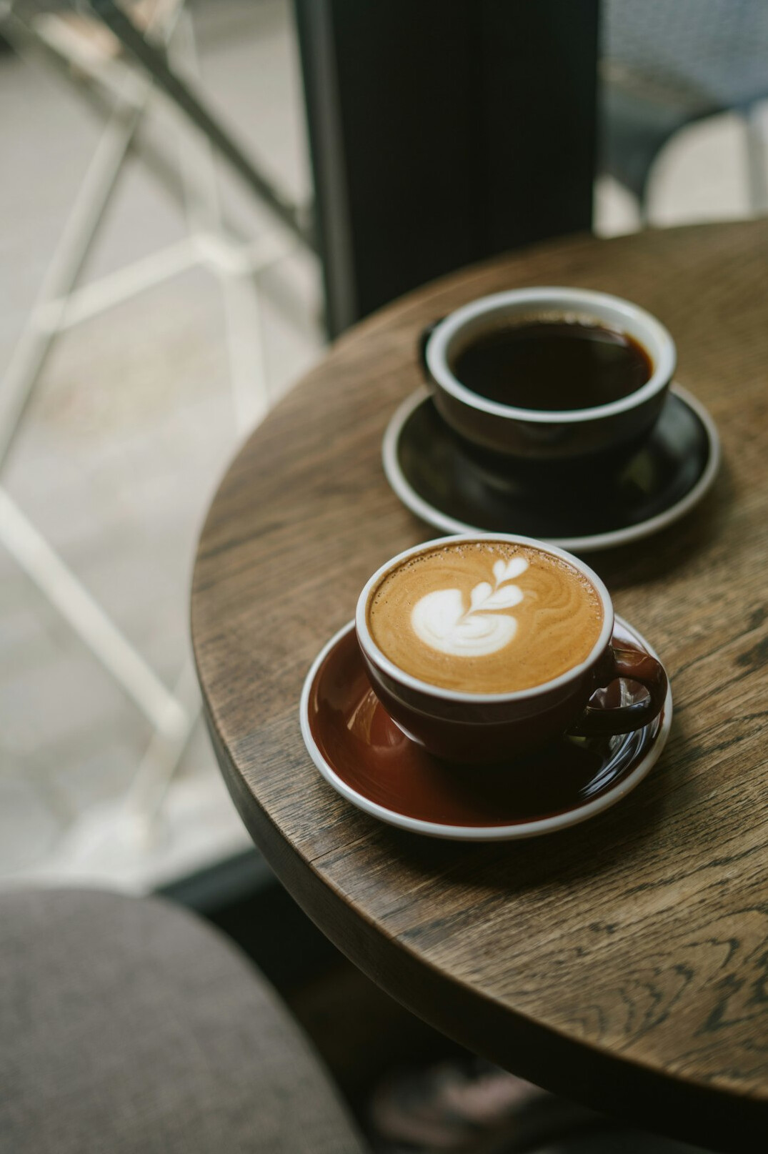 Two cups of coffee on a small cafe table